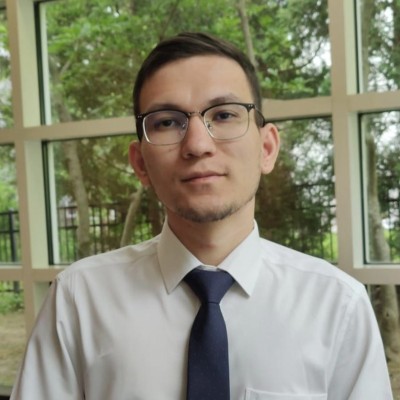 Portrait of Abhisan Ghimire, wearing glasses, a white shirt and a navy tie